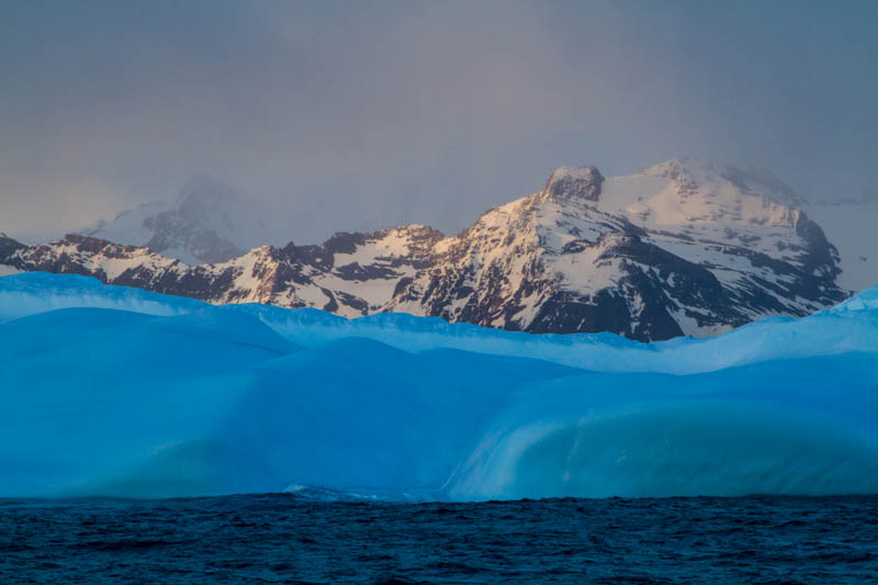 Iceberg And Mountains At Sunrise